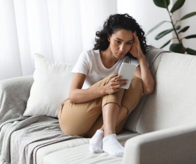 woman at home, on her couch, considering counseling