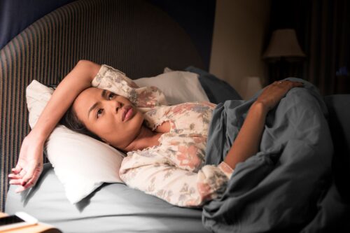woman with depression laying in bed with lamp light on