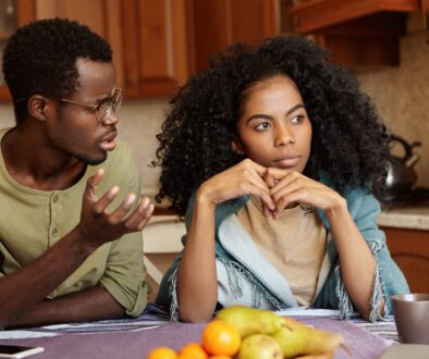 couple at kitchen table who are angry at one another and wife looks annoyed
